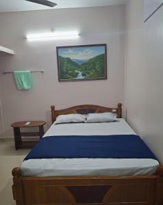 Una cama en un dormitorio con un cuadro en la pared. en Saravana HomeStay, en Tiruvannāmalai