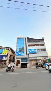 a building with people riding motorcycles in front of it at Hotel Nova Vista in Rajkot