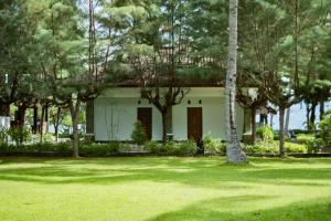 Una pequeña casa blanca con árboles delante. en Janitra 1 BR Standar Room ZN304, en Gili Air