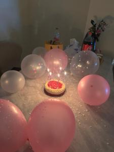 a birthday cake with lit candles on a table with balloons at Shams Wa Bahar Vacation Homes Rental in Dubai