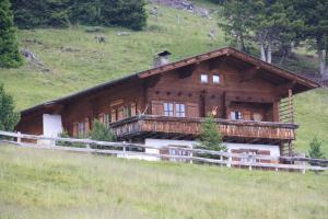 a large wooden house on a hill with a fence at Kristemoarhütte in Gaimberg