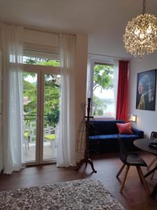 a living room with a blue couch and a chandelier at Jewel on Lake Garda in Garda with Lake view in Garda