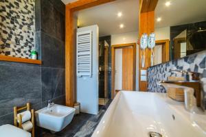 un baño con bañera y lavabo en HARLEY STYLE APARTAMENT, en Muszyna 44 fotos más