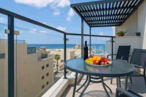 a table with a bowl of fruit and a bottle of wine on a balcony at חלום לים - סוויטות מדהימות עם מרפסת לים באשקלון in Ashqelon