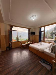 a bedroom with a large bed and large windows at Hotel Moon Blaze " Near Mall Road " Bonfire ! Open Terrace ! Personal Parking in Manāli