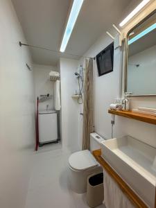 a white bathroom with a toilet and a sink at Aqua Horizon Beachside Skyline Vista Art Condominium in Dauis