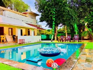 a swimming pool in front of a house at Oceanwood Beachfarm Alibaug in Nagaon