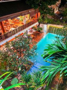 une vue aérienne d'une piscine avec des palmiers et des chaises dans l'établissement Indra Angkor Residence, à Siem Reap