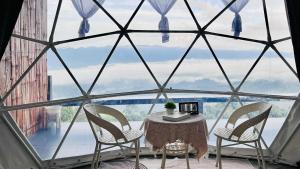 a table and chairs in a room with a large window at โฮมสเตย์ภูชี้ฟ้า in Ban Huai Khu