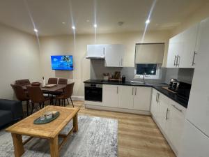 a kitchen with white cabinets and a table and a dining room at Bright & Stylish 3-Bedroom Flat in Ipswich