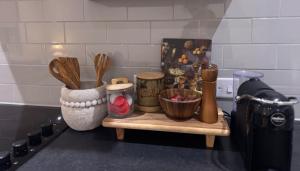 a counter with various kitchen utensils on a shelf at Bright & Stylish 3-Bedroom Flat in Ipswich
