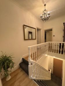 a white staircase in a living room with a chandelier at Bright & Stylish 3-Bedroom Flat in Ipswich +8 photos