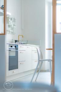 cocina blanca con silla y fogones en Appartement lumineux plein centre, en Chambéry