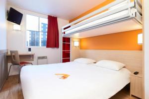 a hotel room with a large white bed and a desk at Première Classe Paris Ouest - Pont de Suresnes in Suresnes +34 photos