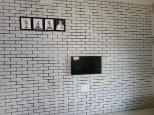 een tv op een witte bakstenen muur met foto's bij Home stay Hotel in Diu