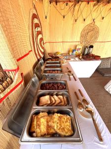 a buffet with several trays of food on a table at Desert Moments Camp in Al Wāşil +28 photos
