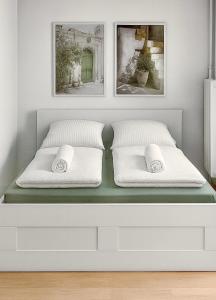 a white bed with two pillows and two pictures at Ella-ruhiges 3-Zimmer-Ferienapartment im Grünen mit Netflix, Koiteich und Terrasse 