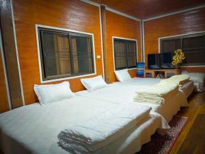 a group of four beds in a room with windows at โฮมสเตย์ พ่อหลวง แม่หลวง บ้านแม่ลาย in Ban Pok Nai