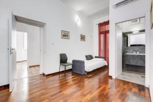 a white room with a bed and a chair at StarHome Colosseo in Rome