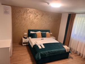 a bedroom with a bed with green sheets and pillows at Pensiunea Noblesse in Căciulata