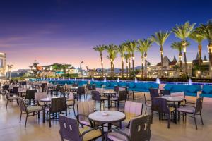 a restaurant with tables and chairs and palm trees at Pickalbatros Aqua Blu Sharm El Sheikh in Sharm El Sheikh