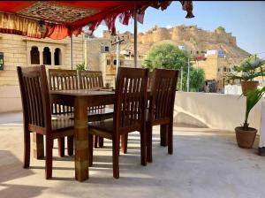 une table et des chaises en bois avec vue sur un château dans l'établissement Classic Villa - Near Jaisalmer Fort, à Jaisalmer 37 autres photos