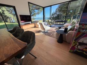 a living room with chairs and a tv and large windows at Vue mer Bretagne Villa d'architecte in Plérin