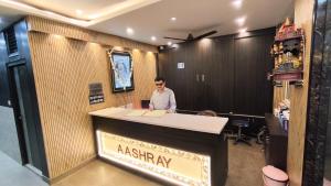 a man standing behind a reception desk in a room at Hotel Aashray in Haridwār