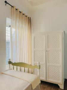 a white bedroom with a bed and a window at La Maison de haut in Tunis