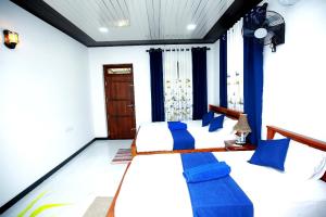 Un dormitorio con dos camas con almohadas azules. en Lisky Villa Blue Beach Hiriketiya, en Dikwella