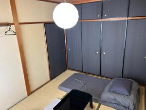 a small room with a bed and a lamp at Guest House YADOKARI in Hirakata