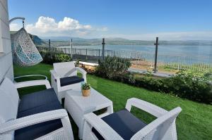 a patio with white chairs and a table with a view of the water at Levication Tiberias Luxury Private Pool Apartments in Tiberias