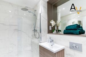 a bathroom with a shower and a sink and a mirror at Luxury Two-Bedroom Apartment - Free Wi-Fi, Close to Station, Ideal for Relocation Guests by AV Hughes Properties in Milton Keynes +37 photos