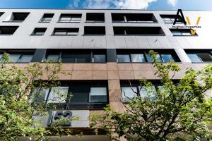 an office building with trees in the foreground at Luxury Two-Bedroom Apartment - Free Wi-Fi, Close to Station, Ideal for Relocation Guests by AV Hughes Properties in Milton Keynes