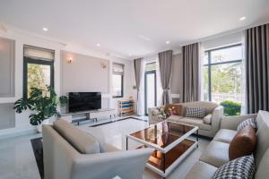 a living room with white furniture and a tv at Mây Hoa Tiên Relax - Villa in Xuan An +27 photos