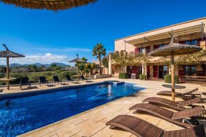 a swimming pool with chairs and umbrellas next to a building at Finca Mar des Teix in Manacor