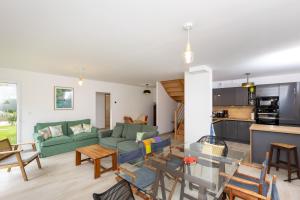 a living room and kitchen with a green couch at Villa Les Charmettes in Saint-Lunaire