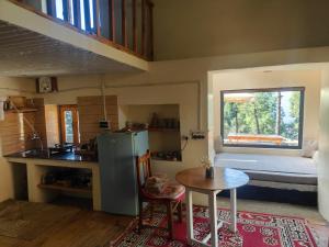 a kitchen with a refrigerator and a table and a window at Astitva Binsar in Hawālbāgh