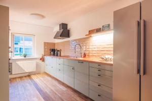 a kitchen with white cabinets and a stainless steel refrigerator at Noorderzon in Buren +23 photos