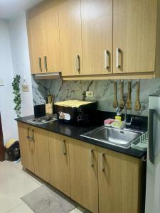 a kitchen with wooden cabinets and a sink and a microwave at Shell Residence Pasay City in Manila