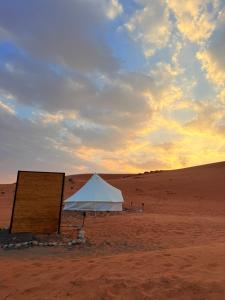 une tente blanche au milieu du désert dans l'établissement Bedouin Stars, à Ḩawīyah