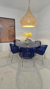a dining table with blue chairs and a chandelier at Riad house Lyabaïana,piscine climatisation, hammam, vue mer in Tangier