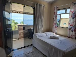 a bedroom with a bed and a balcony at Suítes Carla e Carol in Praia de Araçatiba