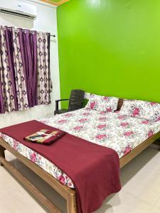 a bed in a room with a green wall at Ramchandra home stay in Malvan