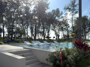 - une piscine avec des chaises blanches dans un parc dans l'établissement The Sunshine Beach Family Suite with Pool, à Layan Beach 38 autres photos