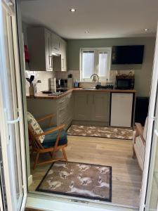 a kitchen with green cabinets and a chair and a table at Woodland View in East Harling +14 photos