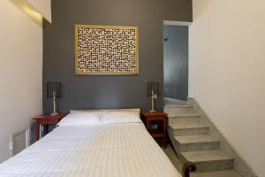 バレッタにあるMagic romantic escape in the heart of Vallettaのベッドと階段があり、壁に絵が飾られている寝室