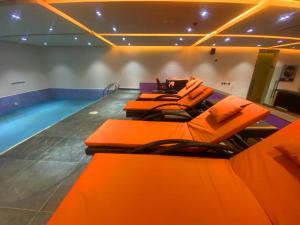 a pool room with orange chairs and a swimming pool at The Cordis Hotel, Ikeja in Ikeja