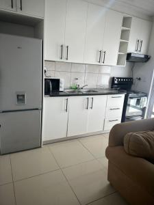 a kitchen with white cabinets and a refrigerator at Dwellers Double in Grassy Park