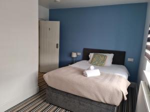 a bedroom with a bed with a blue wall at Swindon Theobald House - EnterCloud9SA in Swindon
